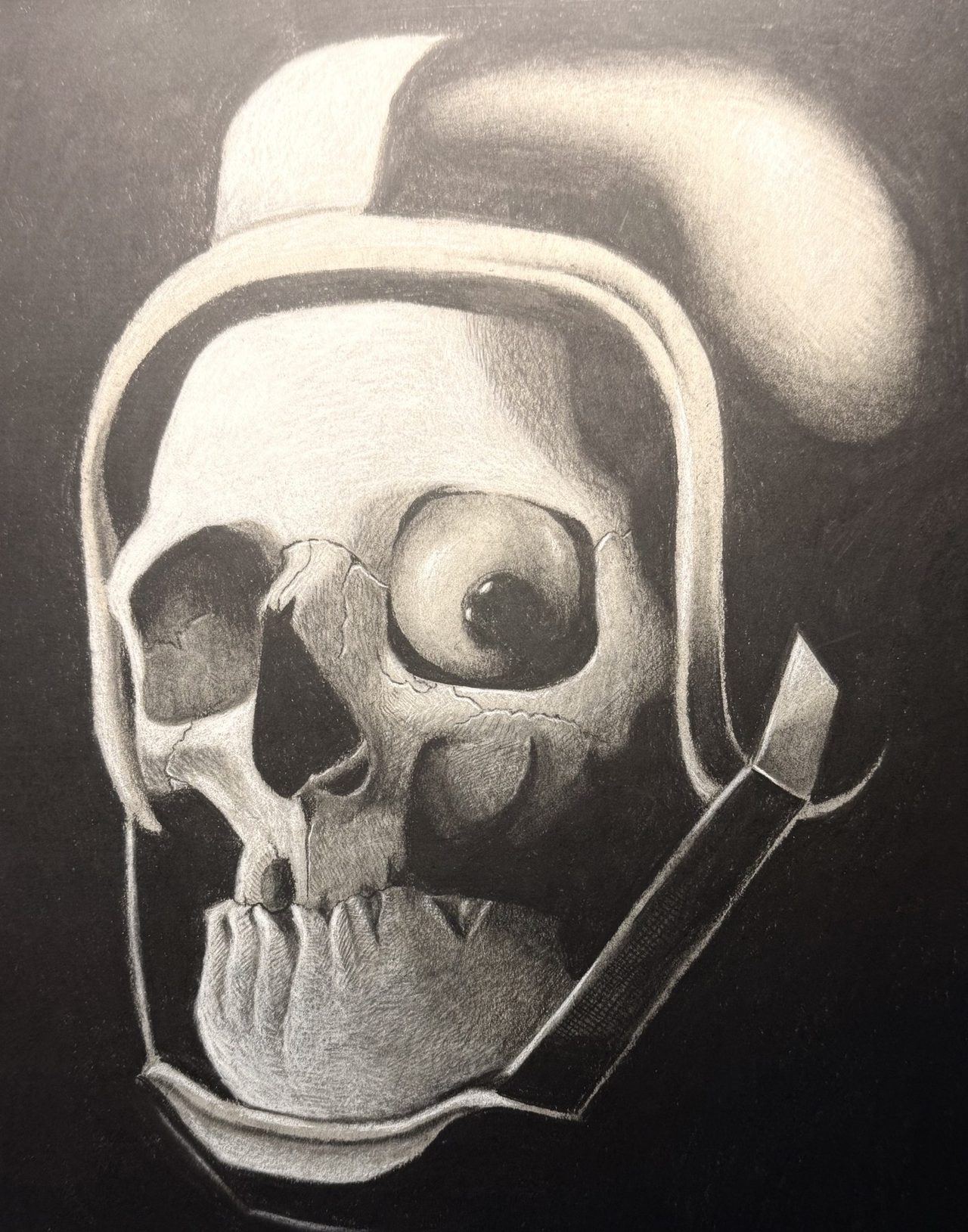 Graphite drawing of a grinning skull inside a helmet with a chin strap, against a black ground